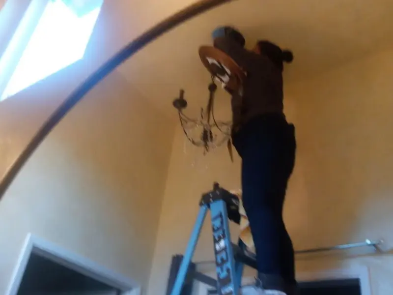 Electrician installing a chandelier in a Winnetka residence